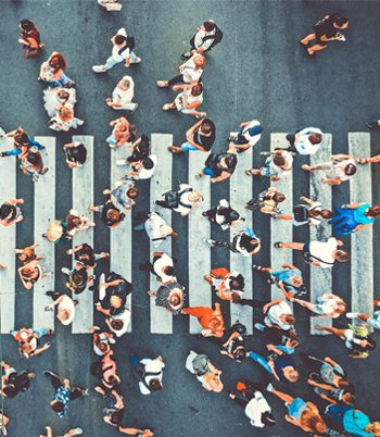 An overhead view captures a diverse group of people walking across a busy street