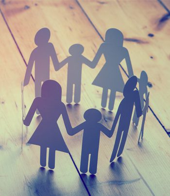 Paper cutout of a family holding hands displayed on a wooden floor