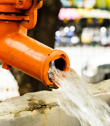 Image of an orange water pipe with water gushing out