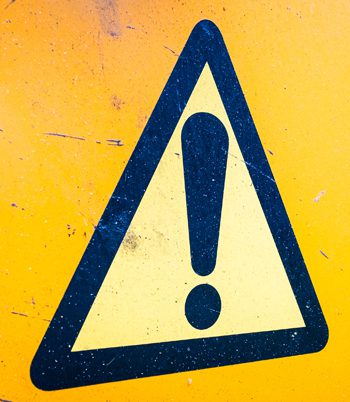 A yellow warning sign featuring a prominent black exclamation mark