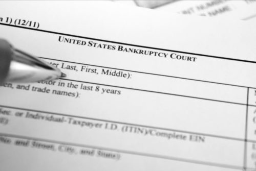 A close-up photo of a pen filling out a bankruptcy form