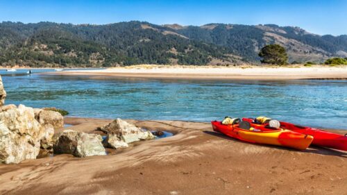 Kayaks on sand next to river